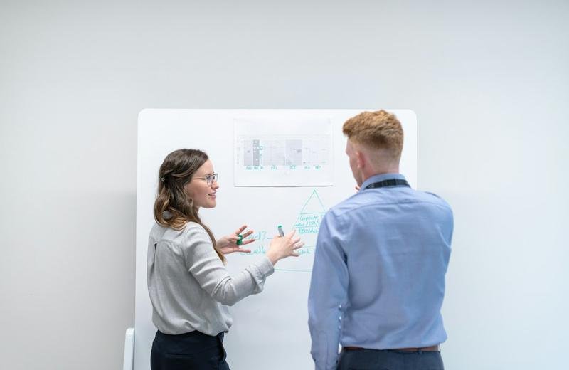 Two consultants reviewing a technology plan at a whiteboard